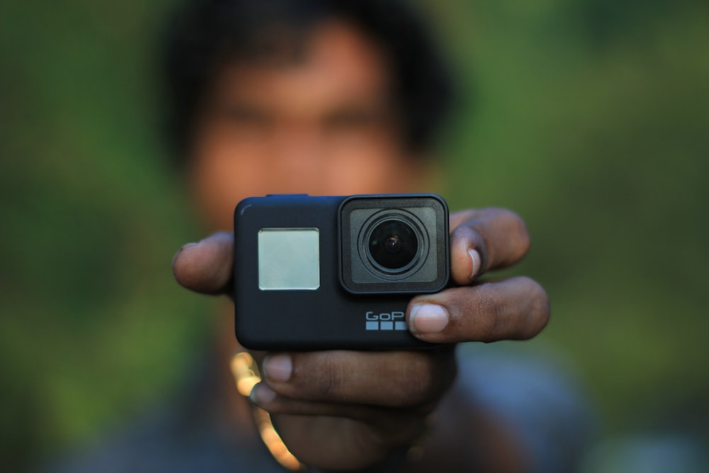 person holding black GoPro HERO