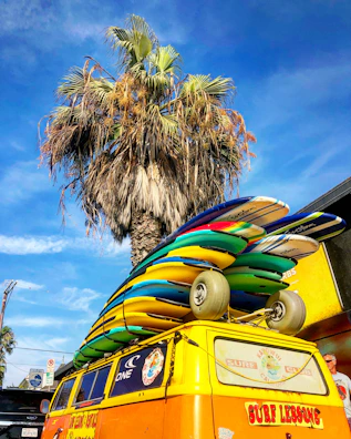 A vibrant red van loaded with surfboards on a sunny beach road.