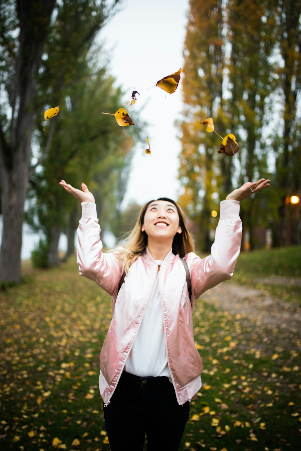 woman throwing leaves during daytime