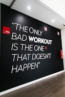 An inspirational quote written on a gym wall amidst workout equipment.