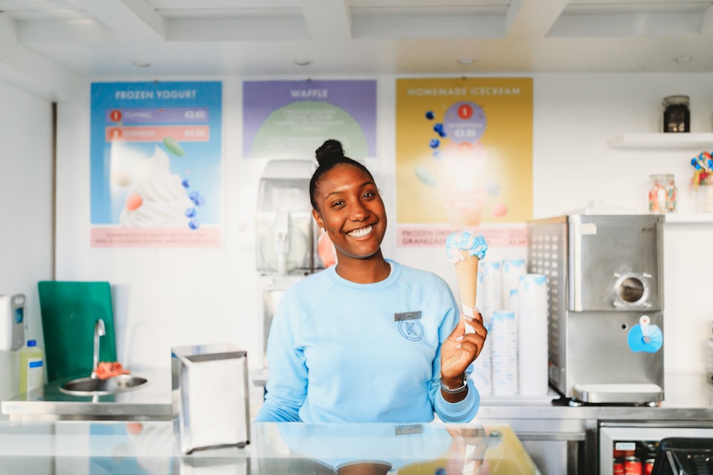 donna sorridente che tiene il gelato dietro il bancone