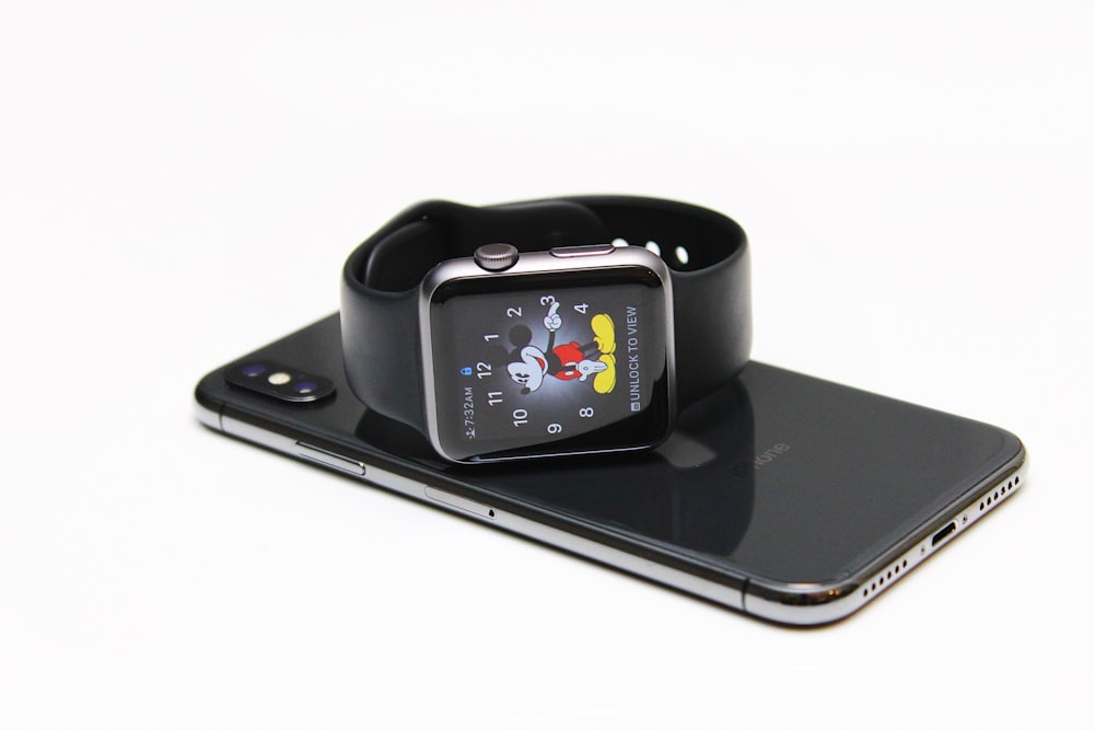 Apple Watch on top of space gray iPhone X