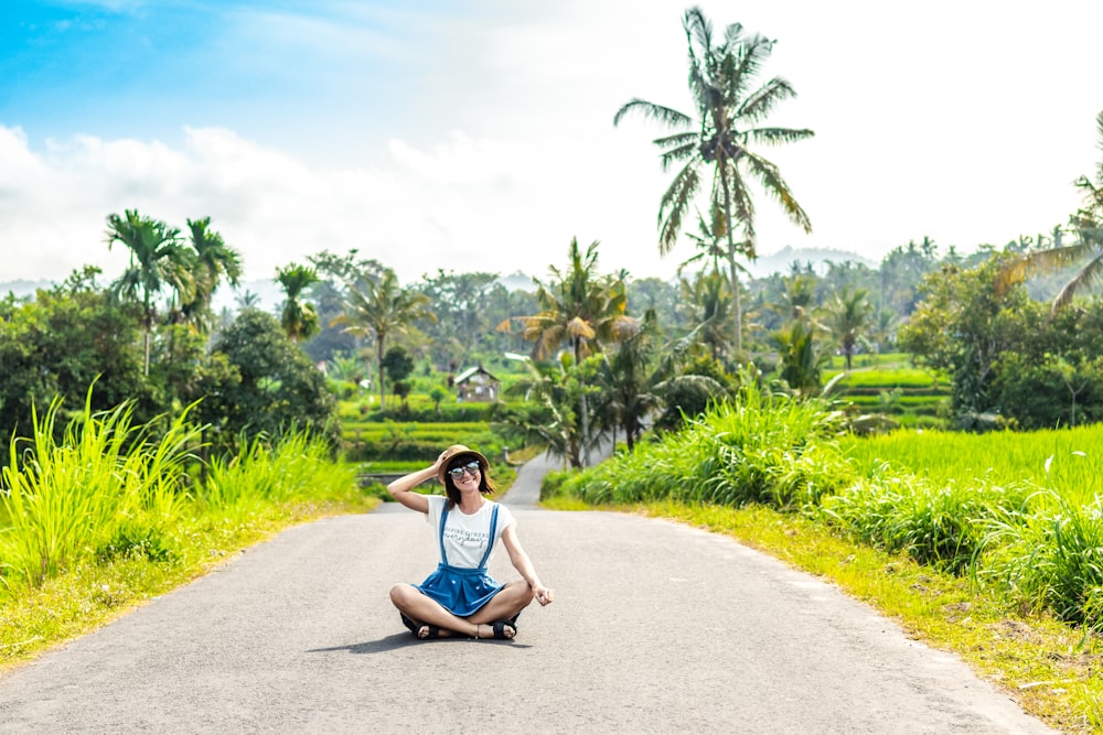 woman sitting in middle of road during daytime