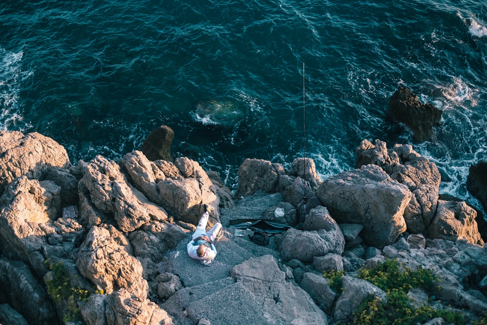 pessoa em rochas perto do corpo de água durante o dia