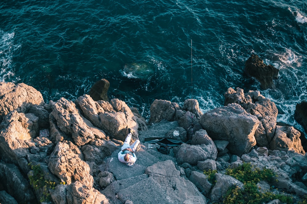 person on rocks near body of water during daytime