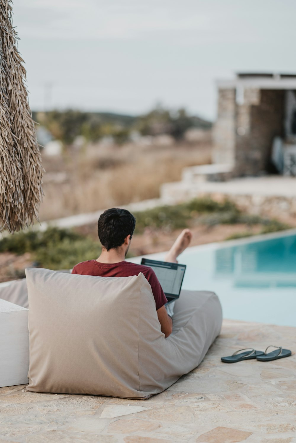 man sitting on lounger while using laptop