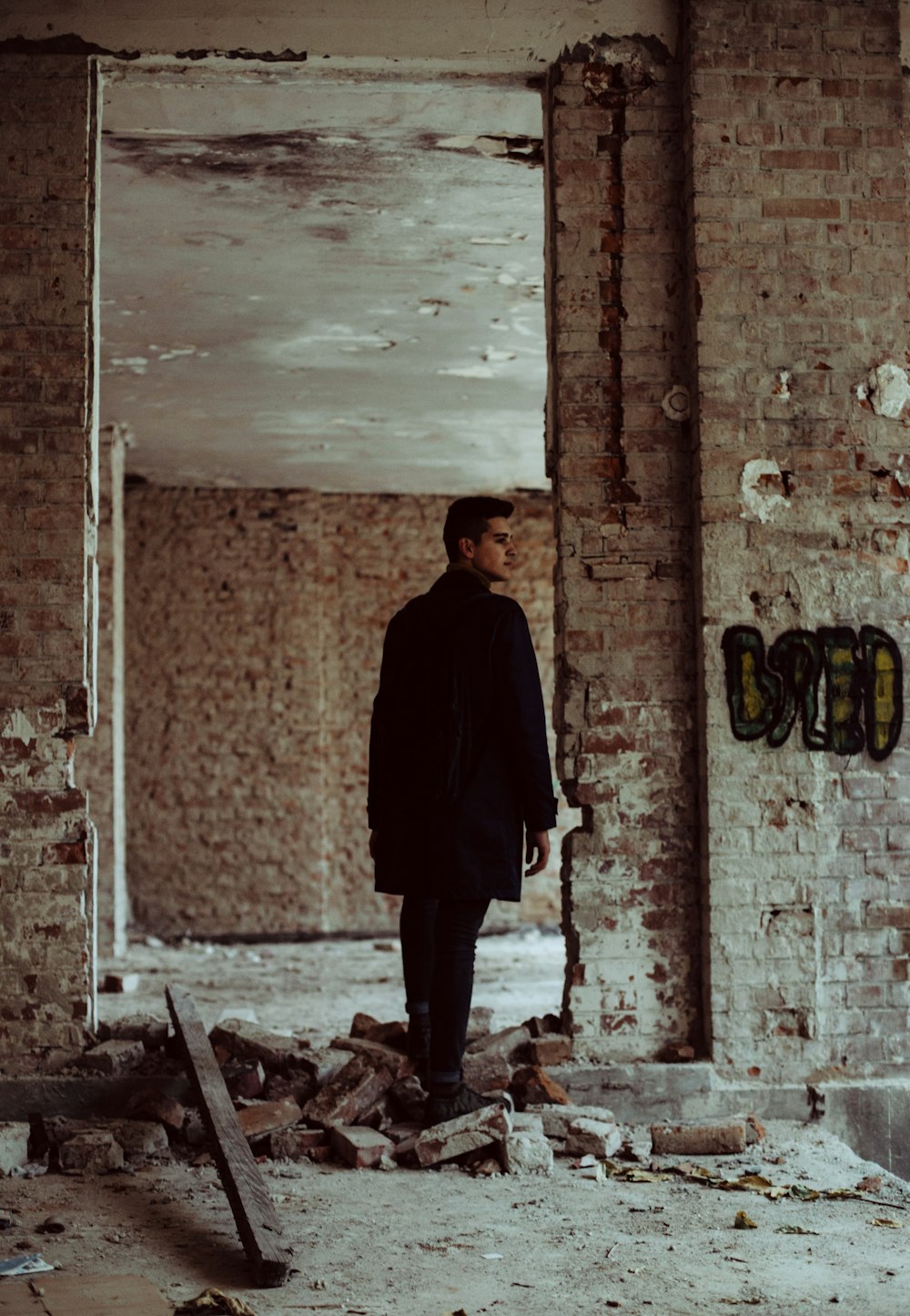man wearing black suit walking in abandoned building