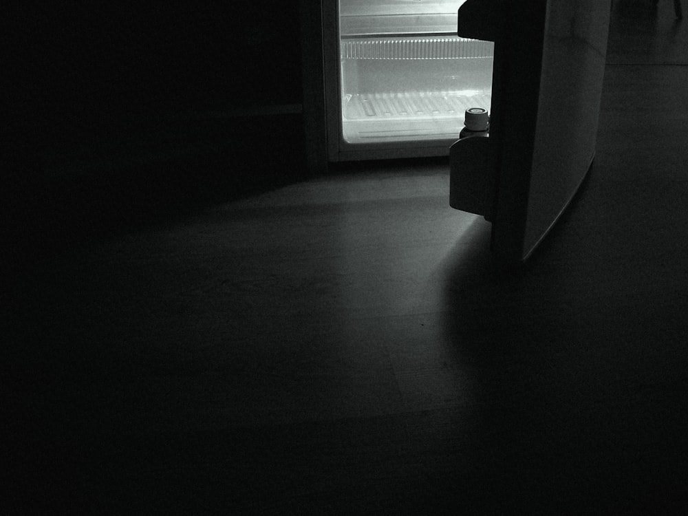 an empty refrigerator in a dark room with the door open