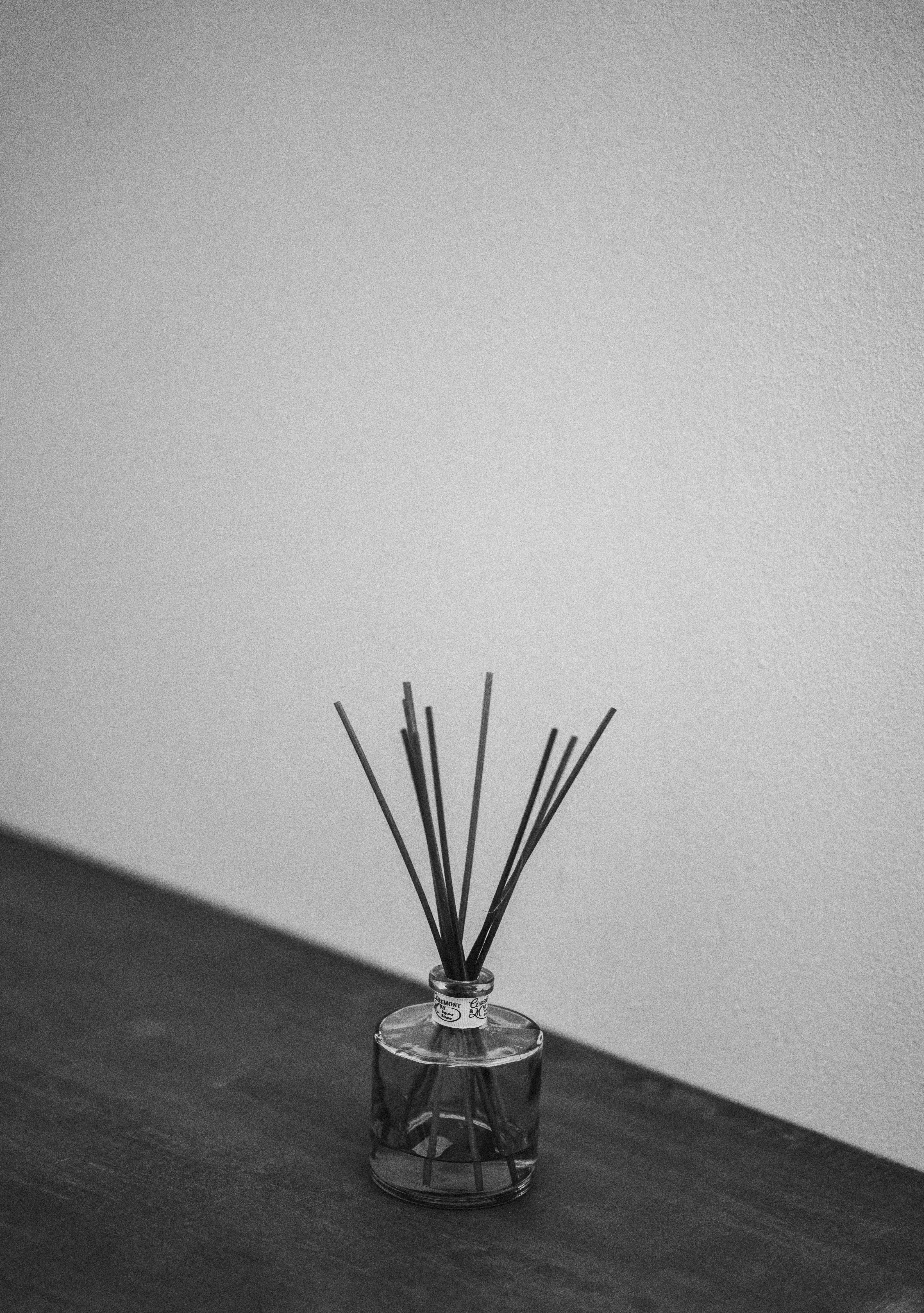 Reed diffuser with amber glass bottle and rattan sticks on wooden shelf, warm home interior