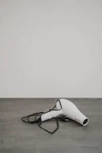 A white hair dryer on a wooden surface