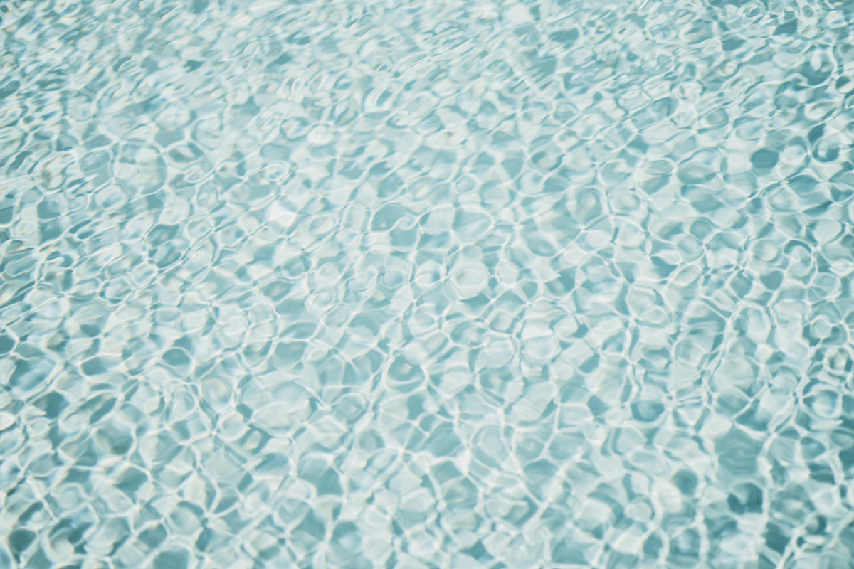 Close-up of clear blue pool water revealing the smooth plaster and tile finish of a freshly resurfaced pool interior