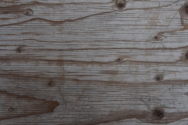 A close-up view of a wooden surface with visible grain lines and knots, presenting a rustic and natural appearance.