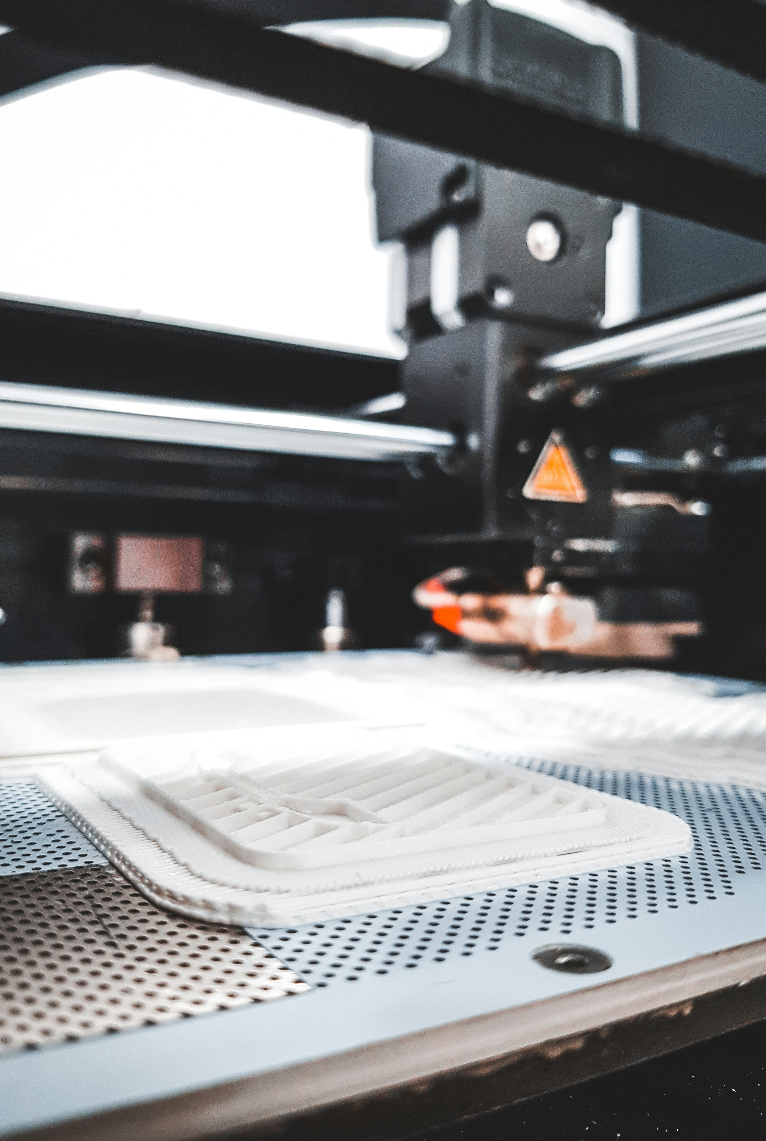 Impresión 3D blanca fabricándose en la cama de una impresora.