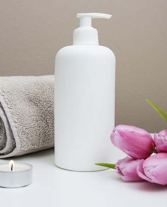 white plastic pump bottle beside pink tulips and gray towel