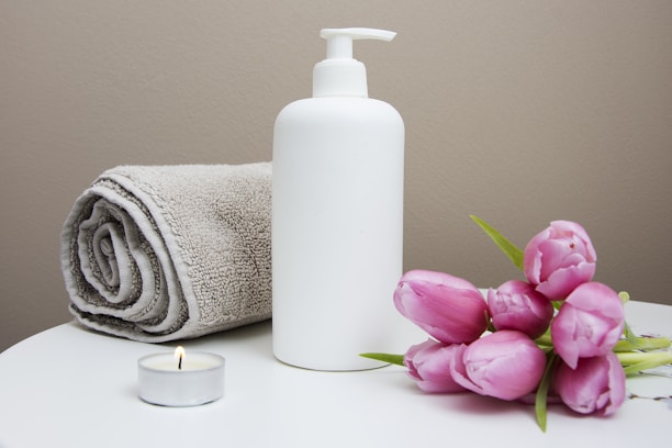 white plastic pump bottle beside pink tulips and gray towel