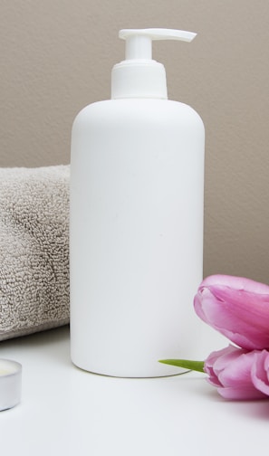 white plastic pump bottle beside pink tulips and gray towel