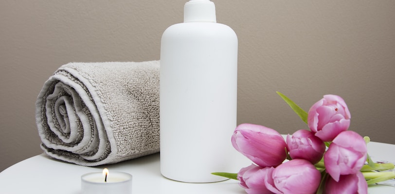 white plastic pump bottle beside pink tulips and gray towel