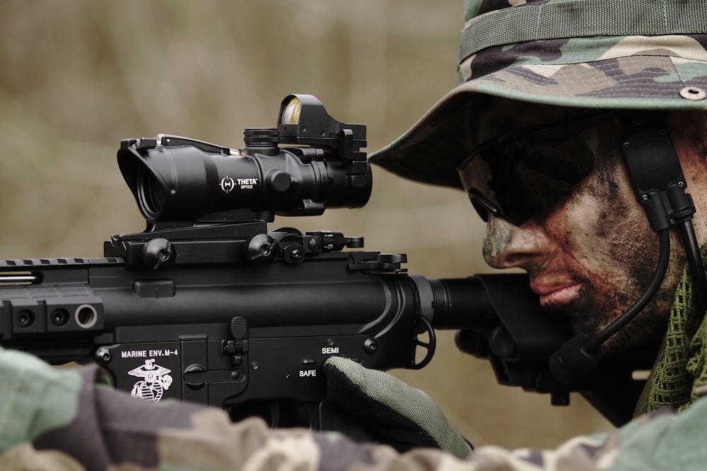Homem em uniforme de camuflagem florestal usando rifle de precisão