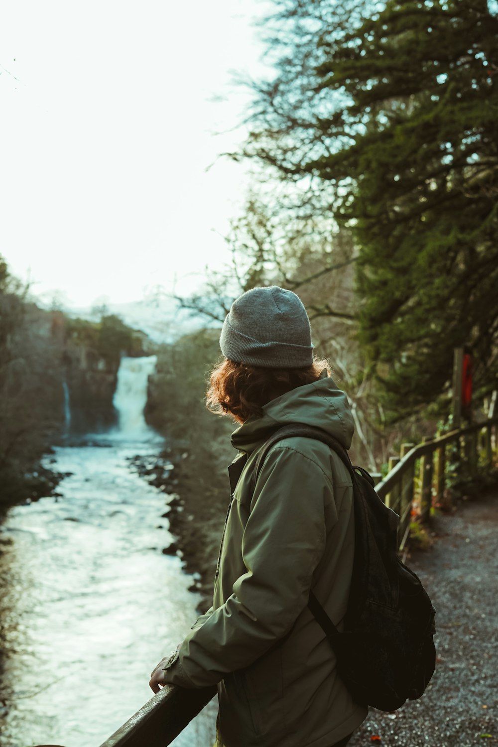 person leaning on bridge above a river