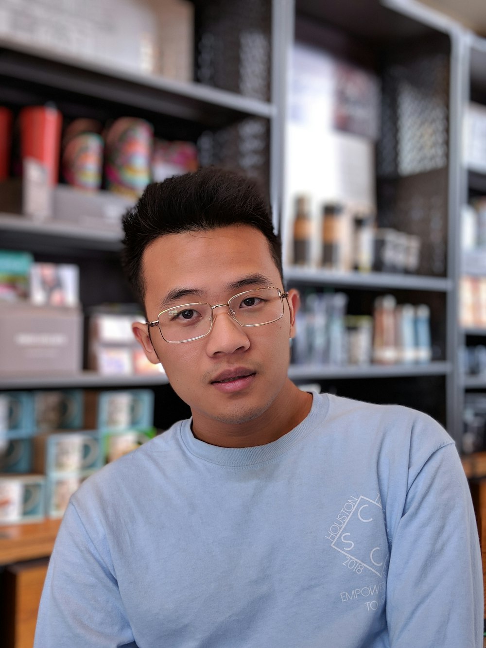 homem usando óculos e camisa azul dentro do café