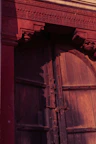 Close-up of rustic wooden door with intricate carvings inviting guests inside.