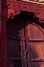 Close-up of rustic wooden door with intricate carvings inviting guests inside.
