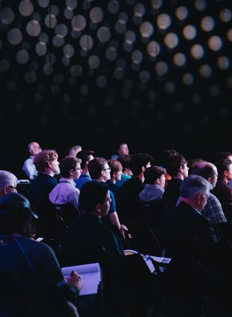 crowd of people sitting on chairs inside room