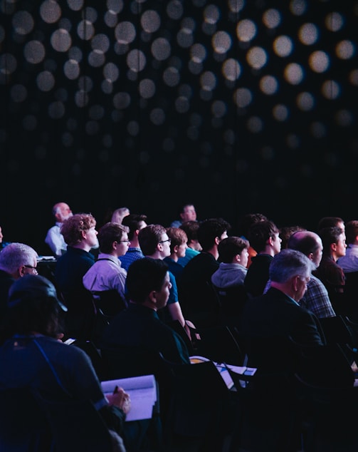 crowd of people sitting on chairs inside room