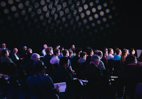 crowd of people sitting on chairs inside room