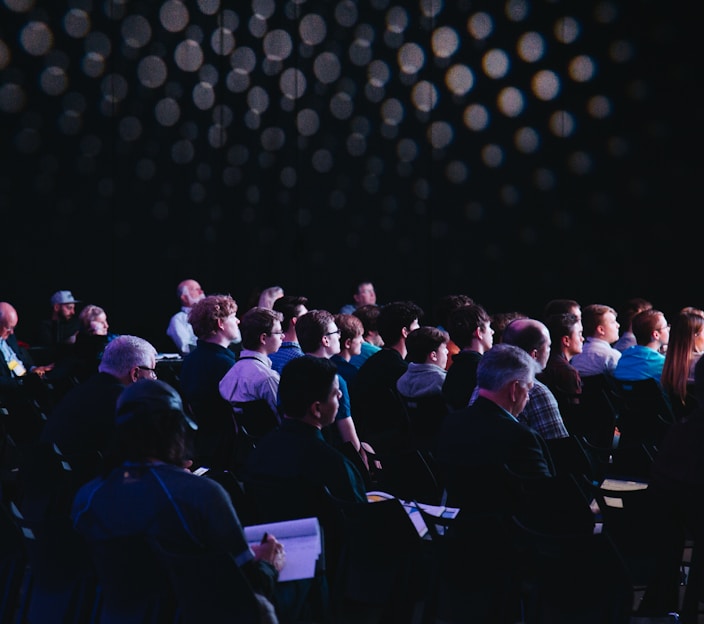 crowd of people sitting on chairs inside room