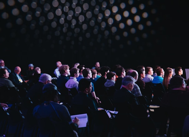 crowd of people sitting on chairs inside room