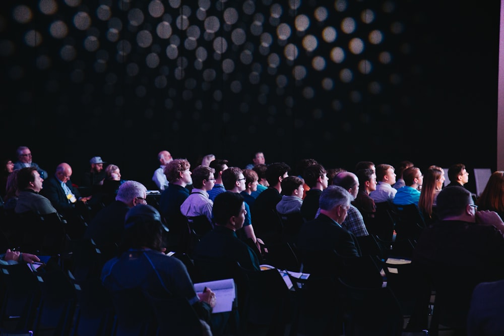 crowd of people sitting on chairs inside room