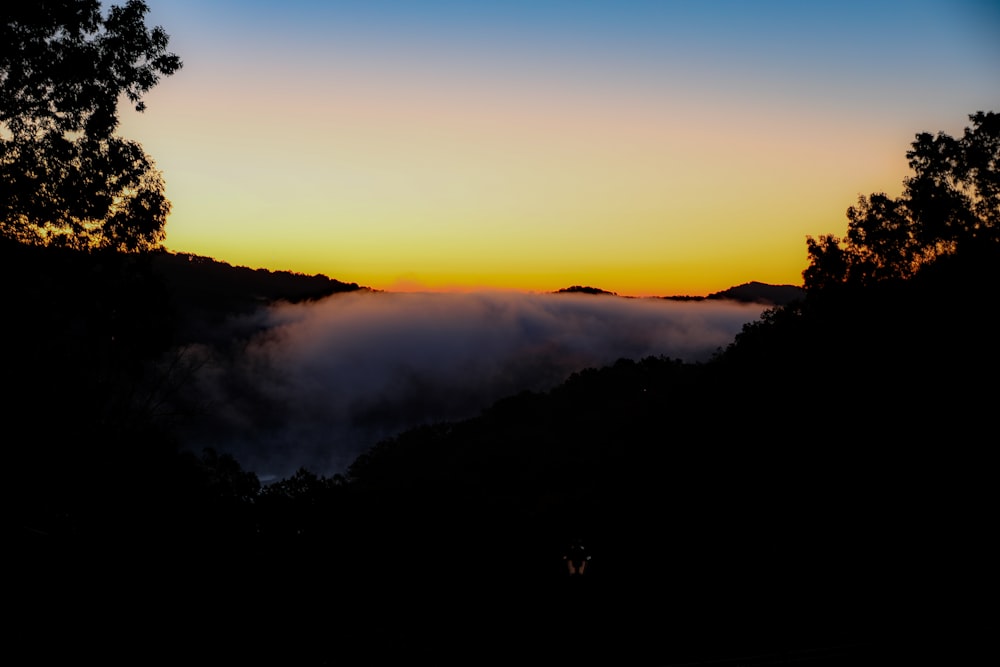 silhouette of mountain with clouds during golden hour