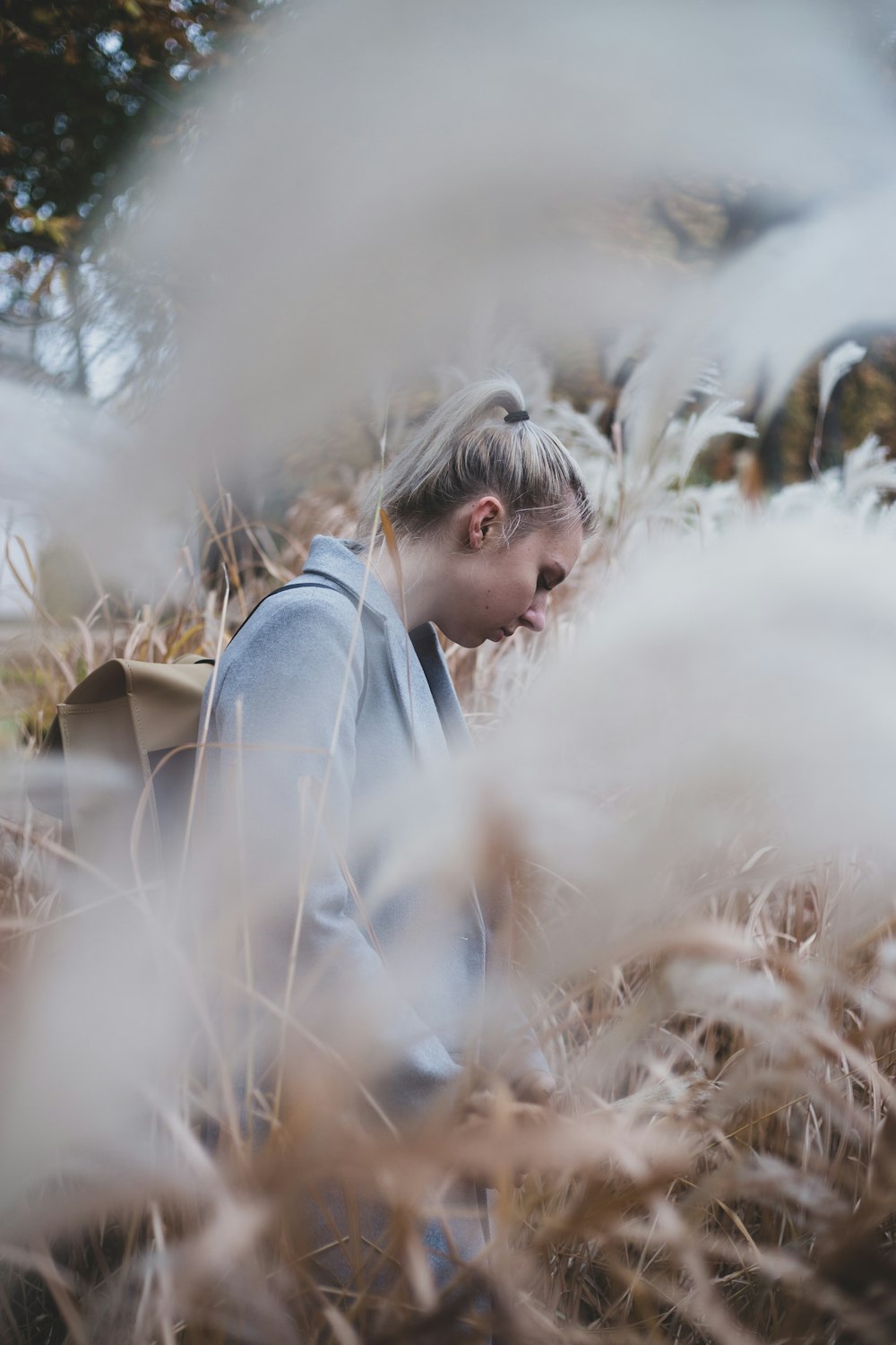 woman wearing white blazer surrounded by brown plants