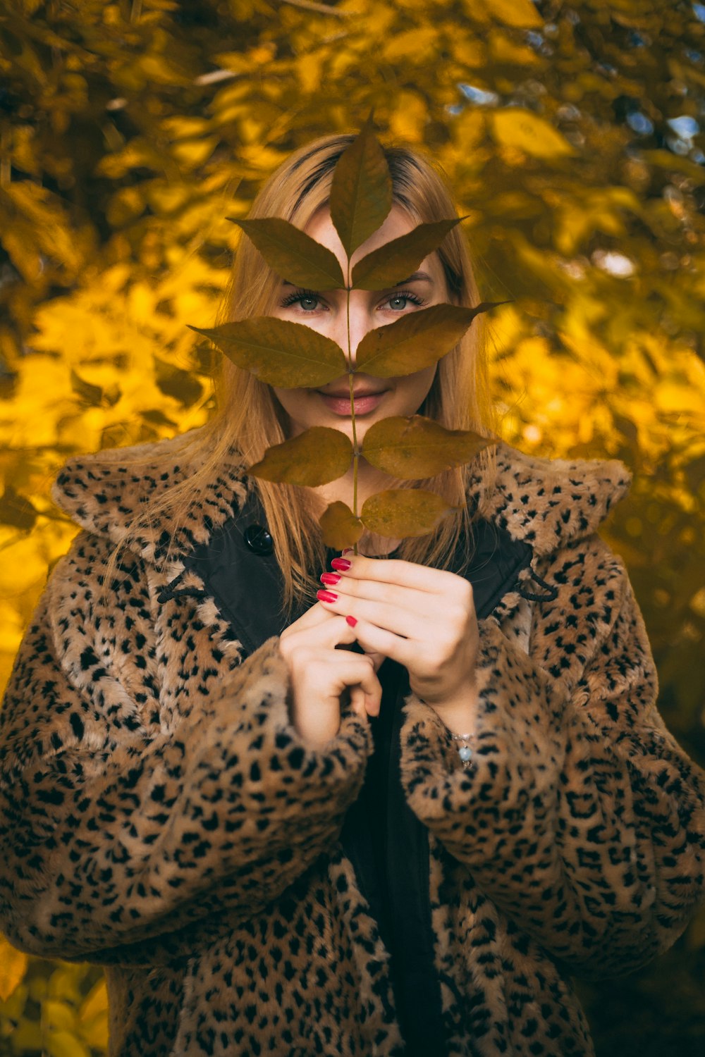 woman wearing leopard coat holding leaves