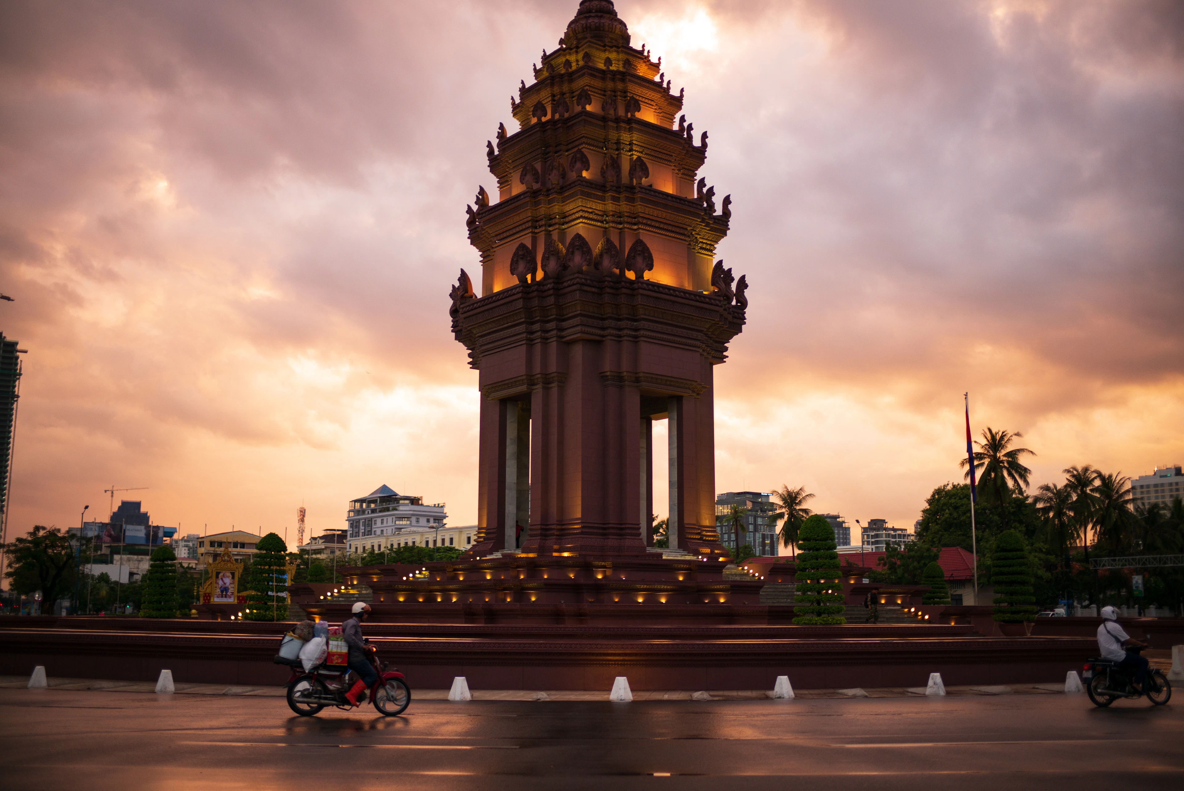 The Independence Monument in Phnom Penh at sunset, a motorbike passing the floodlit lotus-shaped tower