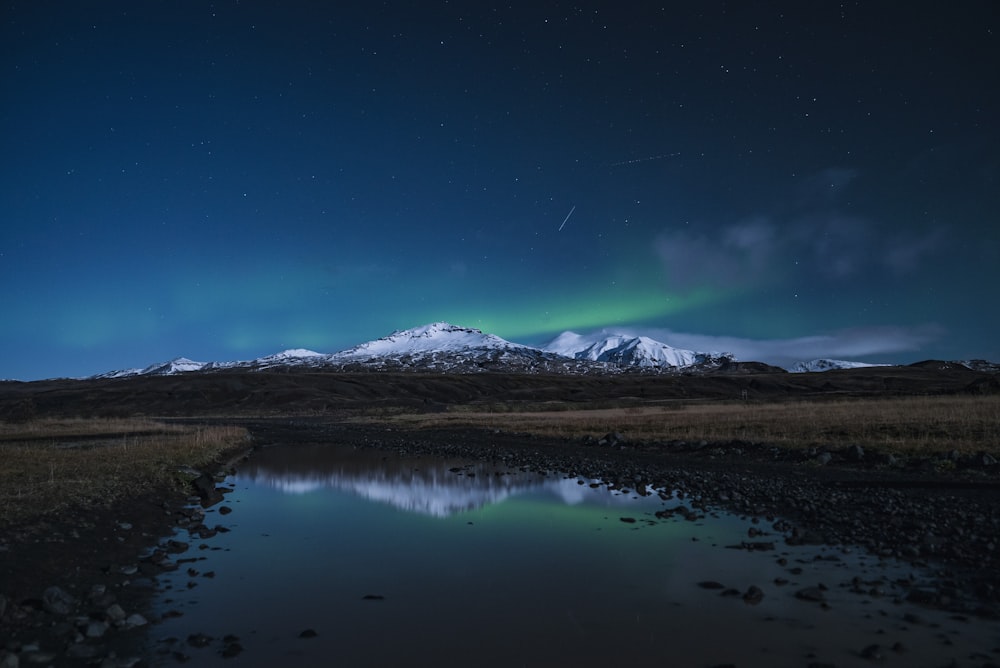 reflection of snow covered mountain on river during night