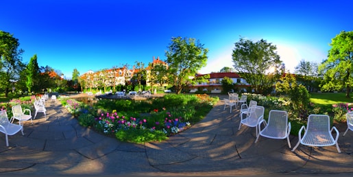 An inviting outdoor space with a mix of lawn, flower beds, and minimalist garden furniture bathed in warm sunlight.