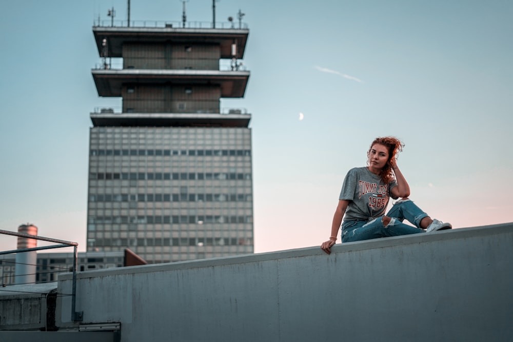 woman sitting on white wall during daytime