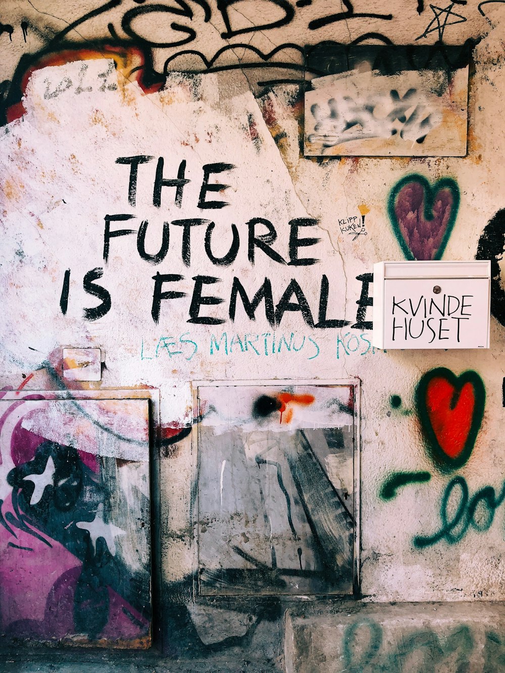 a wall covered in graffiti and a sign that says the future is female