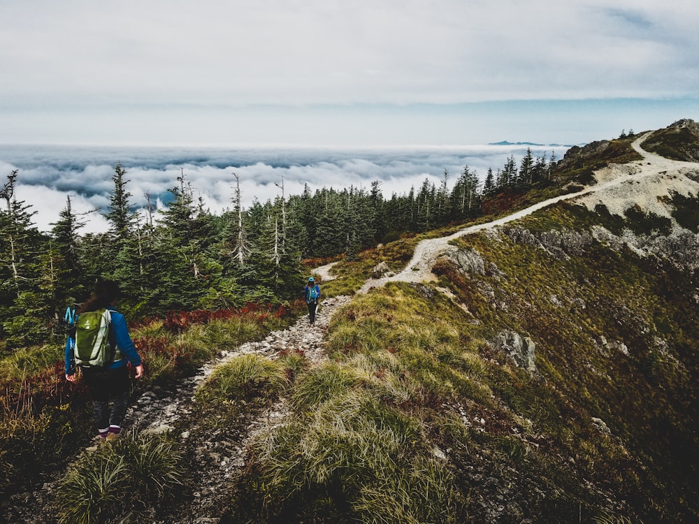 two person's hiking on brown mountain