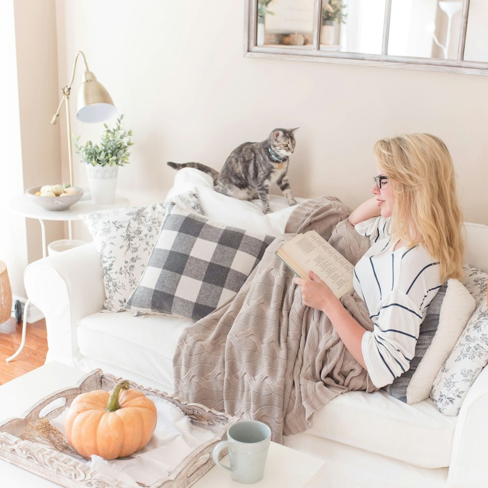 woman reading book on sofa