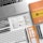 A neatly arranged workspace features a laptop, a UX sketchbook, a keyboard, drawing tools, stencil templates, and wireframe sketches for a mobile app design. The environment appears organized and intended for user experience design work.