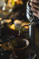 A warm scene of a home barista gracefully pouring water over a V60 dripper, with natural light streaming in.