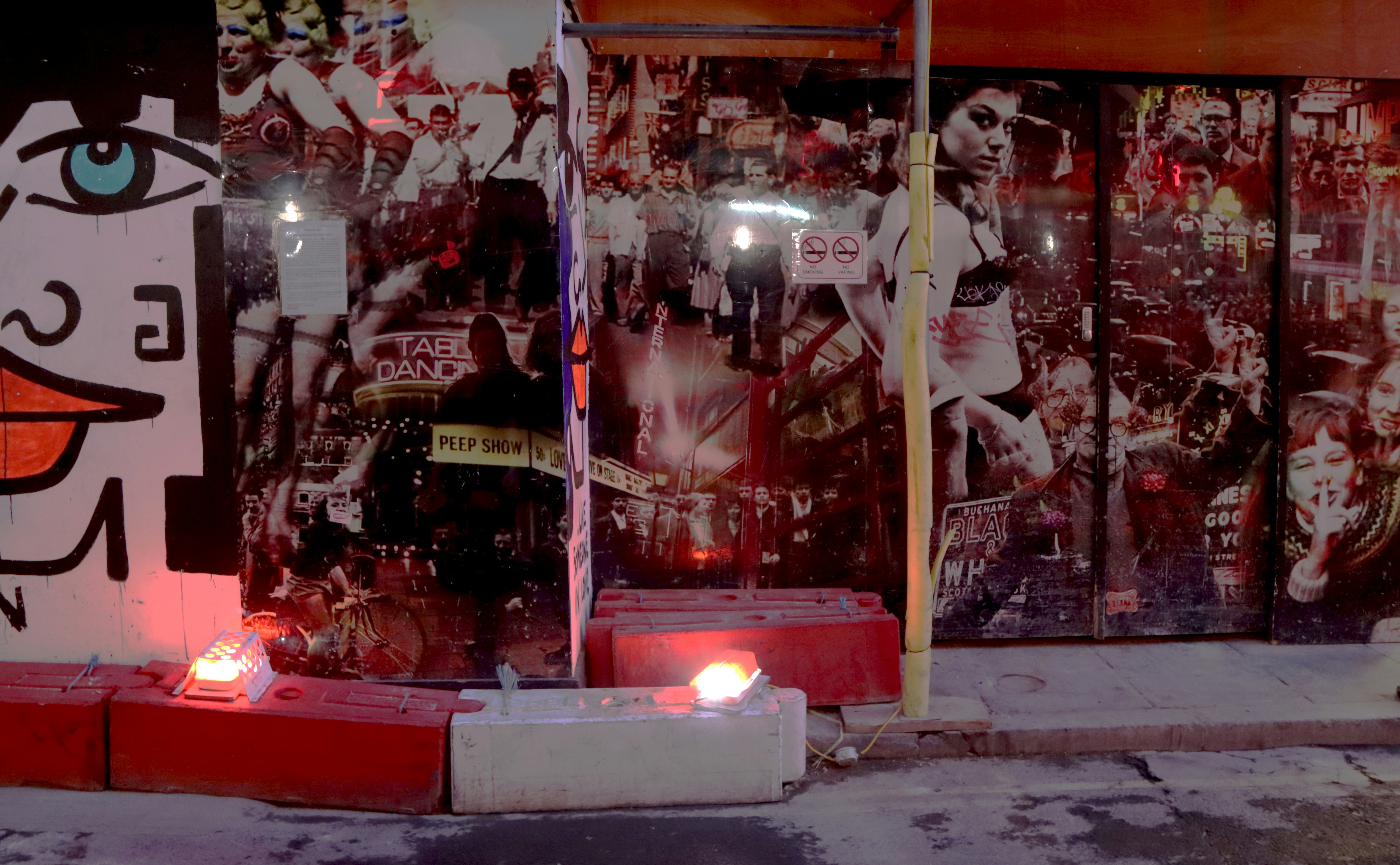 candles in front of wall art, Back street, Soho, London.