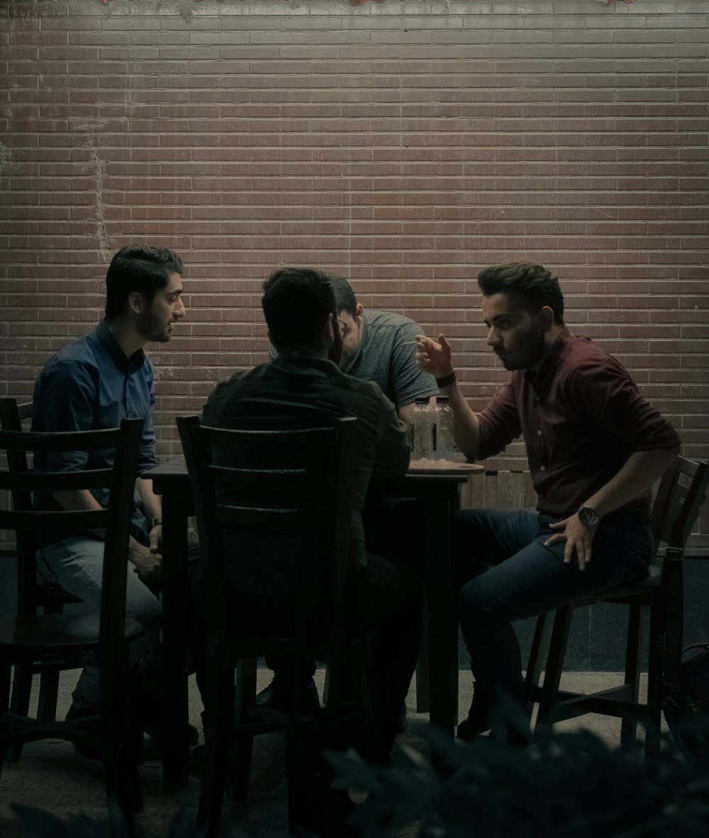 four men sitting beside table
