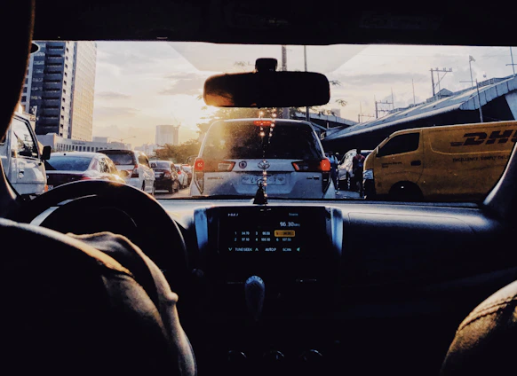A busy delivery van navigating through a vibrant city street during sunset.