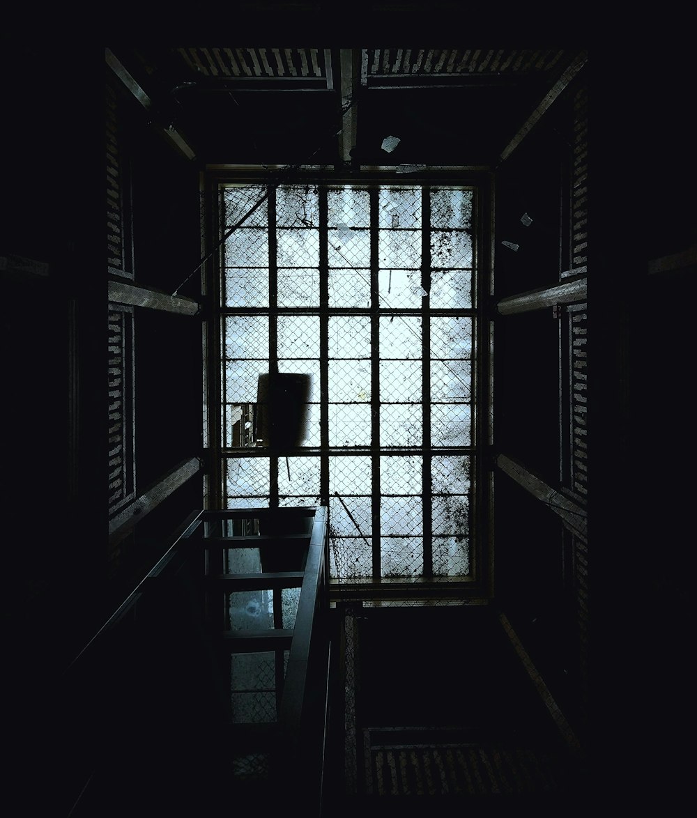 a dark room with a window and a bench