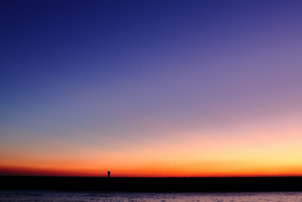 eine person, die bei sonnenuntergang an einem strand steht