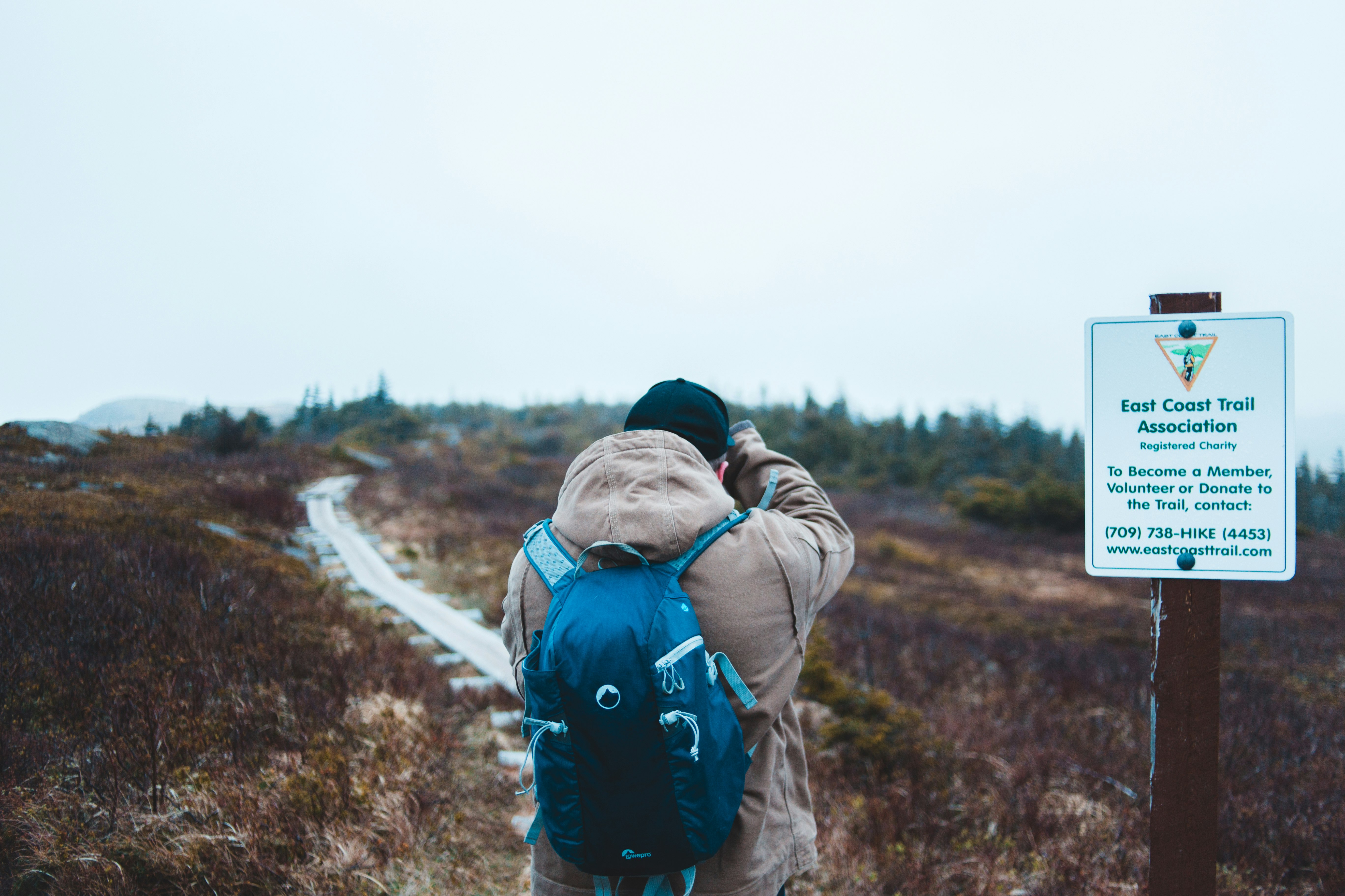 man standing beside road signage in an open field